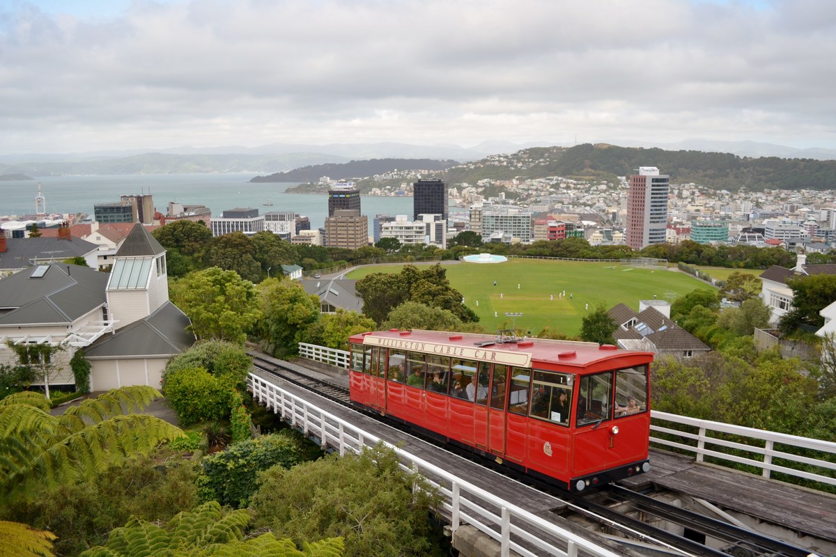 A red Wellington cable car climbing above the city